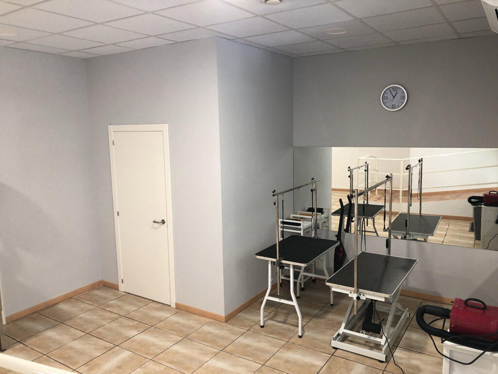 Sala de corte con mesas de peluquería y espejo
